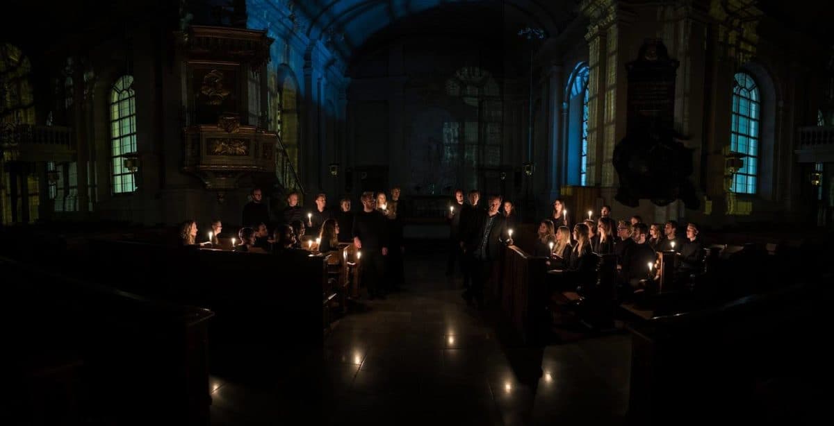foto af en korgruppe, der optræder i en kirke med levende lys