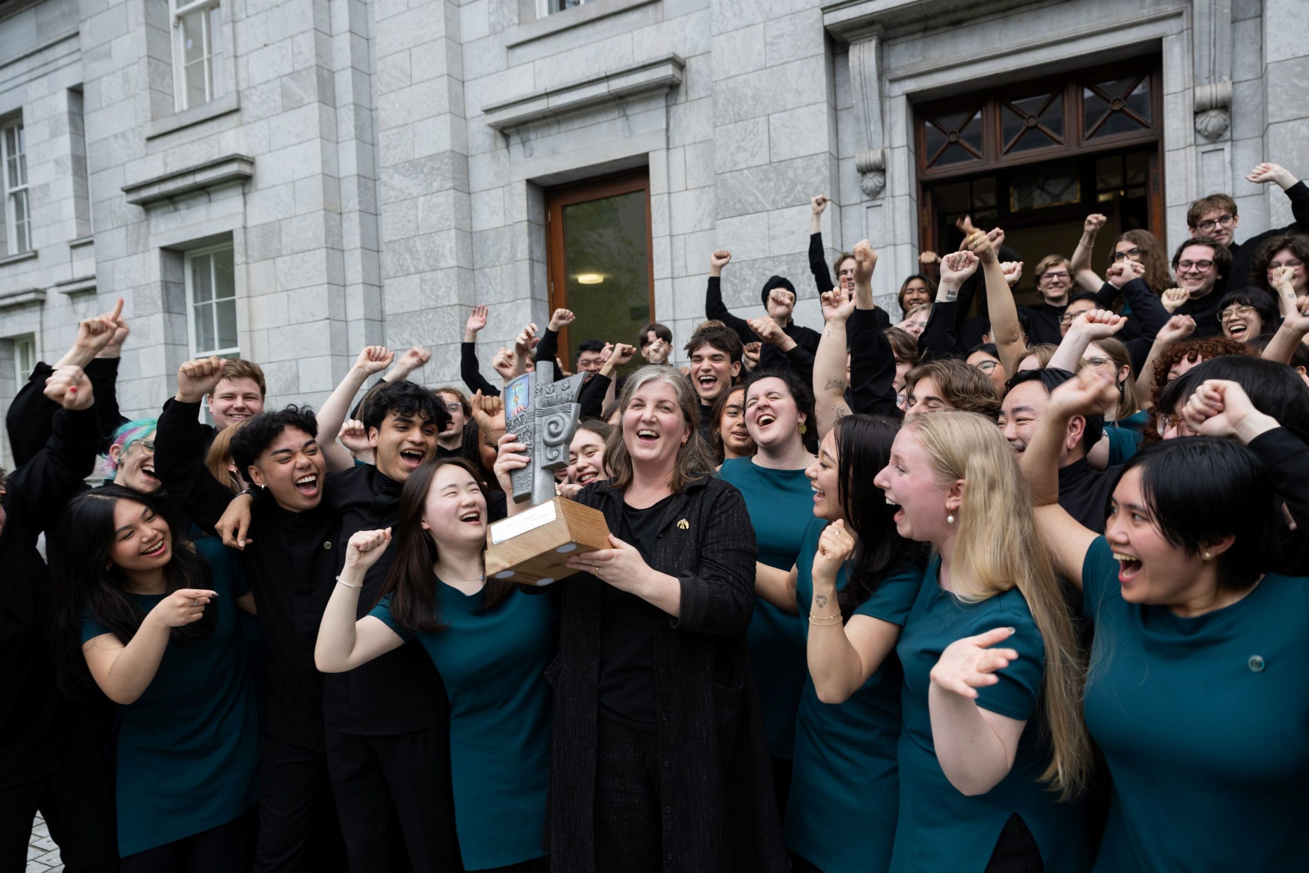 Il Coro Giovanile di Vancouver (Canada) festeggia sollevando il Trofeo Internazionale Fleischmann, vincitore del Primo Premio al Festival Corale Internazionale di Cork, circondato dai membri del coro in festa fuori dal Municipio di Cork.